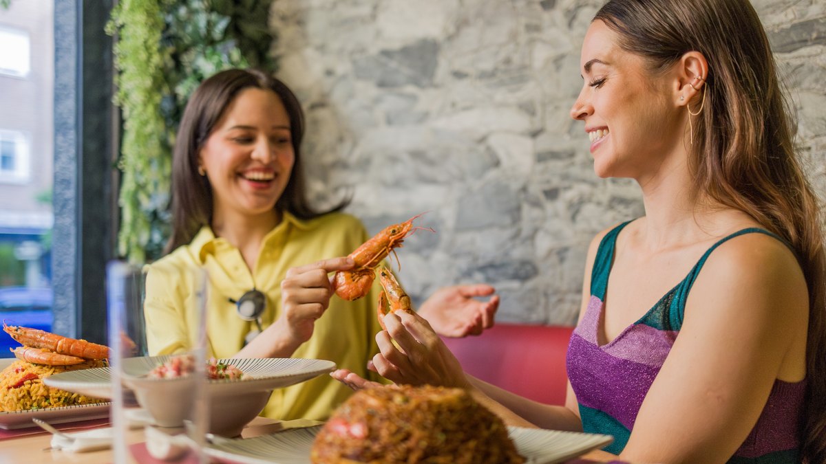 Două femei la masă, mâncând fructe de mare gătite